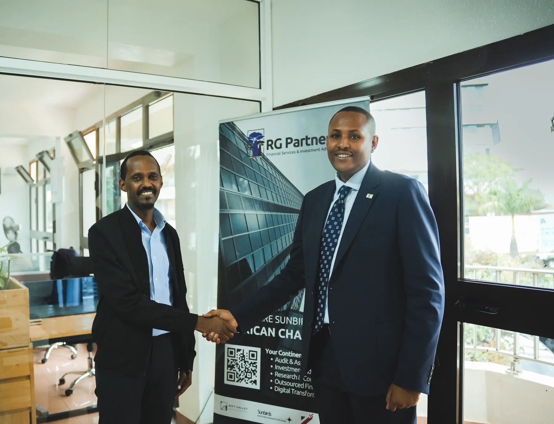 Two RG Partners colleagues shaking hands in front of a Sunbirds banner